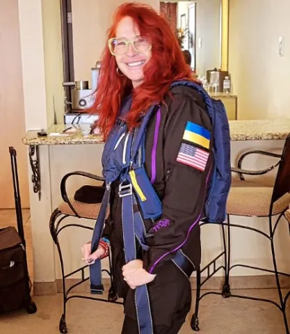 Ліна Бороздіна показує нашиті на рукаві льотного костюма прапори України та США.